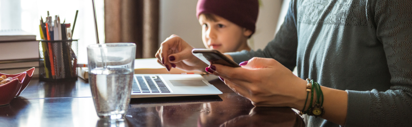 Man in front of laptop, holding phone with little boy beside him