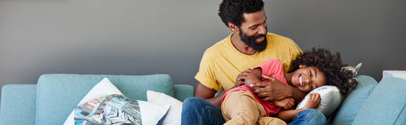 Man and daughter laughing on couch